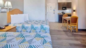 A hotel room with two beds, a desk, a chair, a microwave, and a door. - Studio 6 Bakersfield_2 Full Beds | Smoki (Bakersfield)