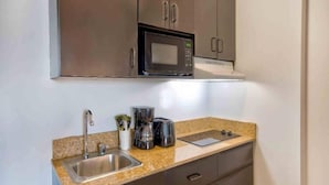 A compact kitchen with a stainless steel sink, a microwave, a coffee maker, and a toaster on a granite countertop. - Studio 6 Bakersfield_2 Full Beds | Smoki (Bakersfield)