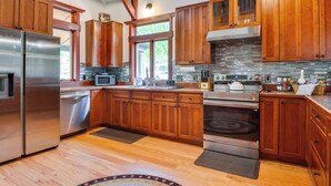 A modern kitchen with wooden cabinets, stainless steel appliances, and a large window. - Hot Tub, Game Room! Stunning Home By Short Sands (York)