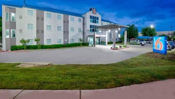 A multi-story hotel with a covered entrance and a parking area.