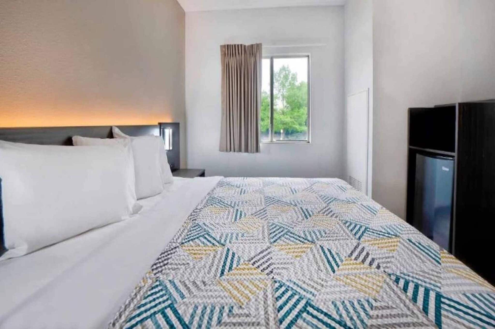 A hotel room with a large bed, a window with curtains, and a TV.