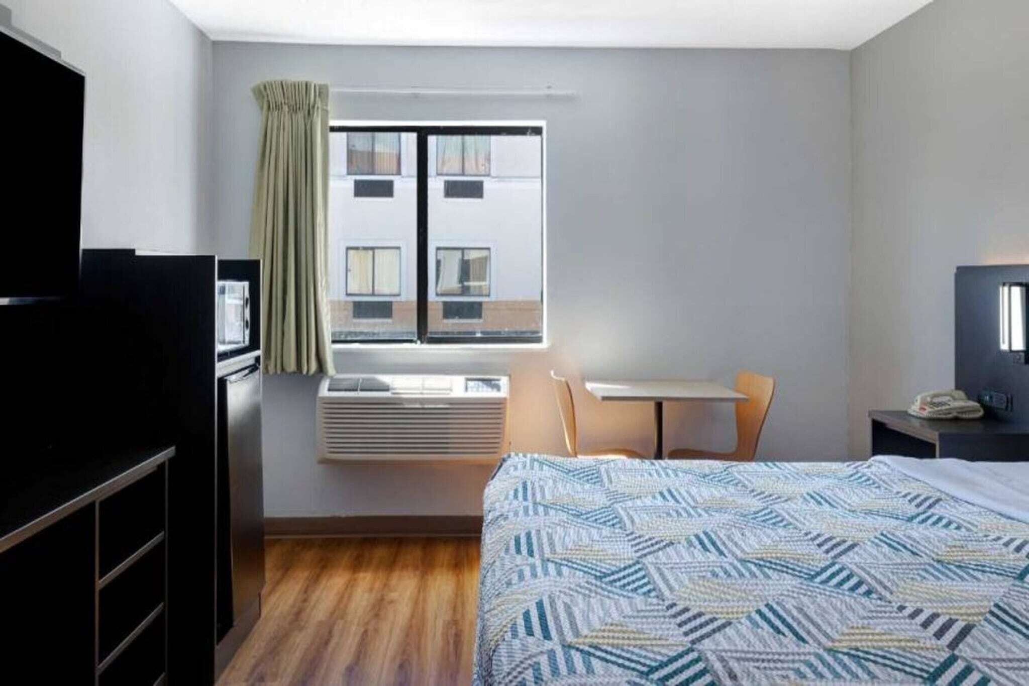 Une chambre d’hôtel équipée d’un lit, d’un bureau, d’une chaise, d’une télévision et d’un appareil de climatisation.