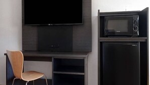 A flat-screen TV mounted on a wall, a microwave, and a refrigerator below it. - 1 King Bed | Smoking (Shepherdsville)