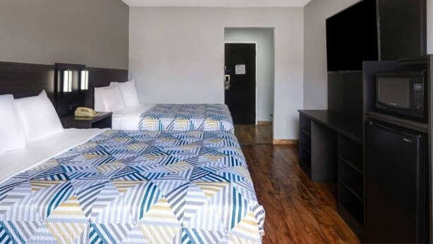 A hotel room with two beds, a TV, a microwave, and a desk. - 2 Queen Beds | Smoking (Shepherdsville)
