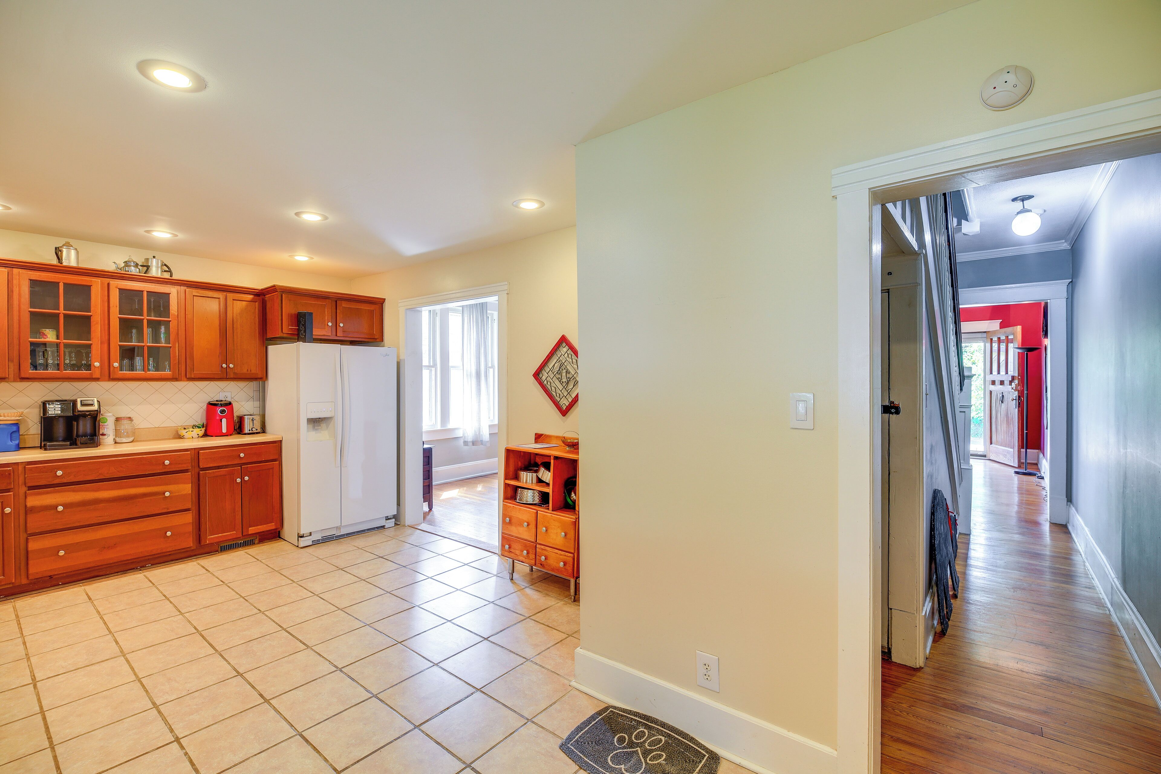 A spacious kitchen with wooden cabinets, a refrigerator, and a dining area with a window.