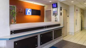 A reception area with a digital display, a reception desk, and a hallway with doors.