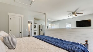 A bedroom with a bed, a ceiling fan, a TV mounted on the wall, and a laundry area visible through an open door. - Walk to Beaches on 30A! Coastal Studio Stay (Santa Rosa Beach)