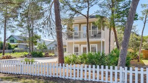 A two-story house with a balcony, surrounded by trees and a white picket fence. - Walk to Beaches on 30A! Coastal Studio Stay (Santa Rosa Beach)