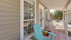 A covered porch with a blue Adirondack chair, a small table, and a door with a window. - Walk to Beaches on 30A! Coastal Studio Stay (Santa Rosa Beach)