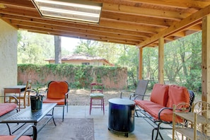Une terrasse extérieure avec des meubles en métal, une table ronde et une vue sur une maison et des arbres.