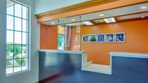 A reception area with a red carpet, a large window, and a wall with framed pictures.