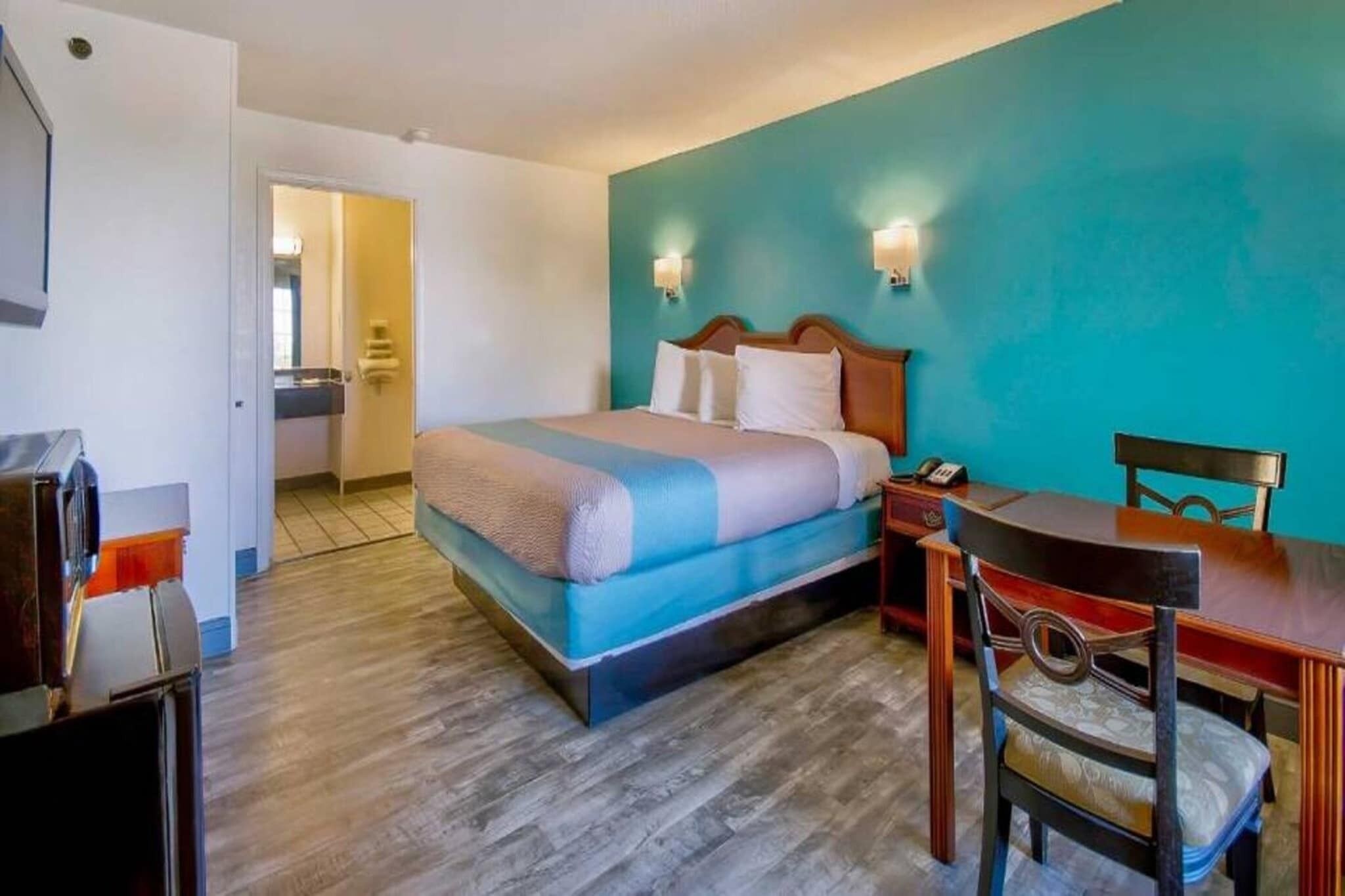 A hotel room with a bed, a desk, and a chair.