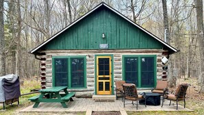 A log cabin with a green roof, a wooden door, and a picnic table with chairs outside. - Hike, Fish, Relax! Park Falls Lodge w/ Guest Cabin (Park Falls)
