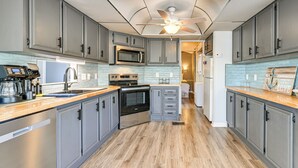 A modern kitchen with grey cabinets, stainless steel appliances, and a wooden countertop. - Amazing Views! Family-Friendly Badin Lake House! (New London)