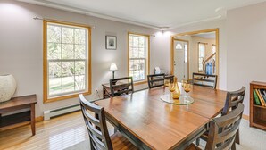 Un comedor con una mesa de madera, sillas y vistas al exterior a través de amplios ventanales.