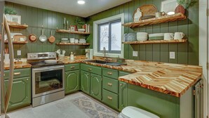 A kitchen with green cabinets, wooden countertops, and various kitchen utensils and dishes displayed on shelves. - Gateway to Nordic Valley! Mtn-View Ogden Home (Ogden)