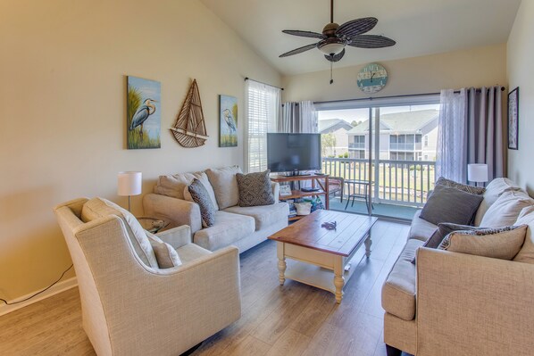 A living room with a sofa, armchairs, a coffee table, a flat-screen TV, and artwork on the walls. - Pool & Hot Tub Access! Waterfront Sunset Beach Gem (Sunset Beach)
