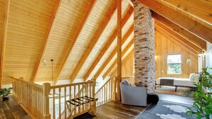 A spacious loft with a wooden ceiling, a brick fireplace, a staircase, and a cozy seating area. - Mount Rainier Views & Hot Tub: Pet-Friendly Cabin! (Mineral)