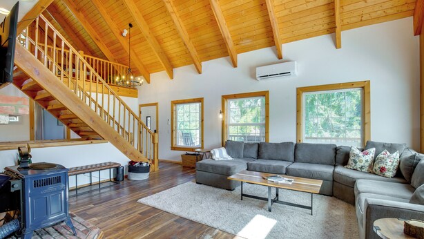 A spacious living room with a wooden staircase, a gray sofa set, and a wood-burning stove. - Mount Rainier Views & Hot Tub: Pet-Friendly Cabin! (Mineral)
