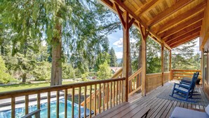 A wooden deck with a pool, outdoor seating, and a view of trees and a distant building. - Mount Rainier Views & Hot Tub: Pet-Friendly Cabin! (Mineral)