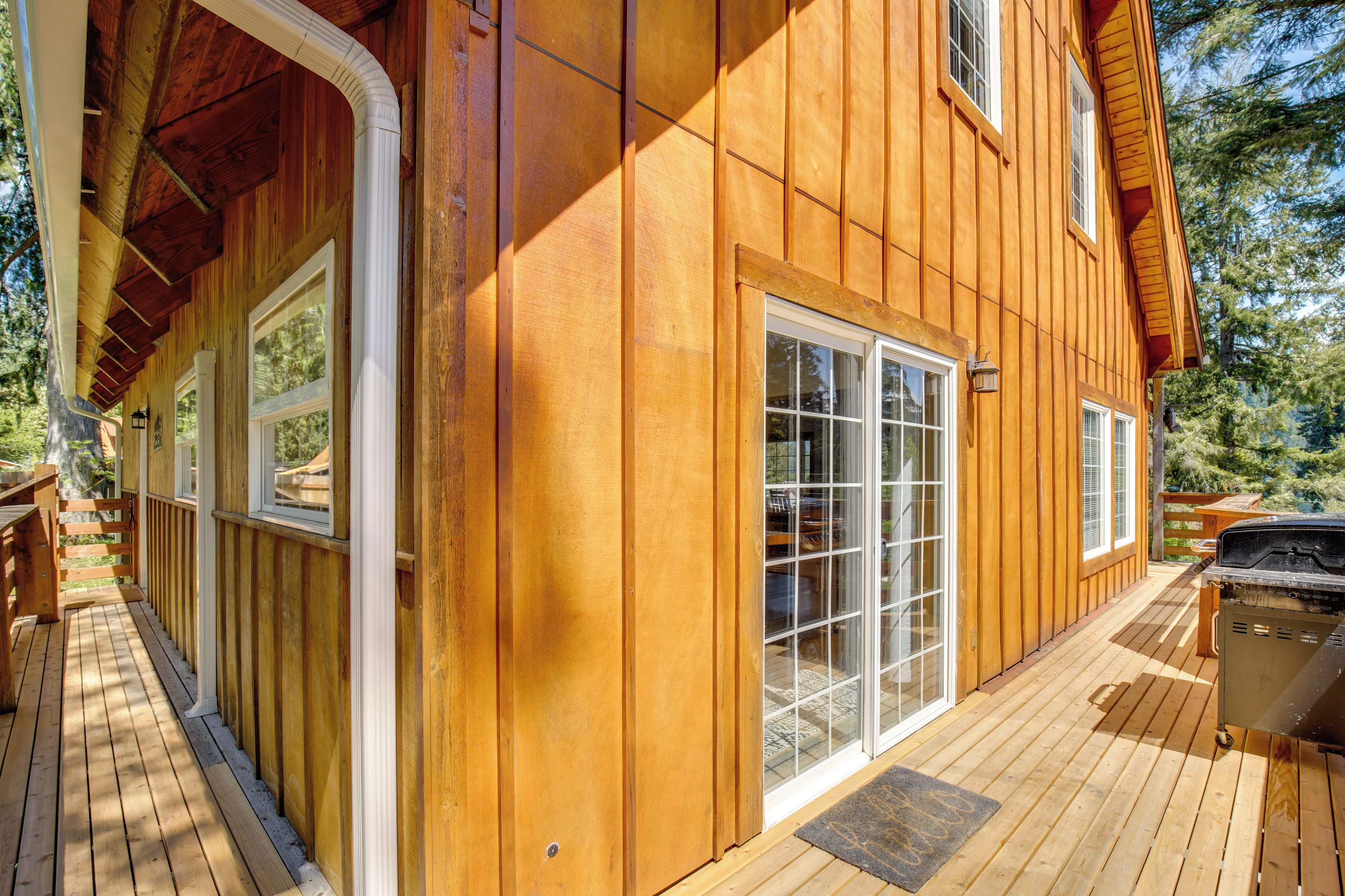 A wooden deck with a grill, a covered porch, and a large sliding glass door.