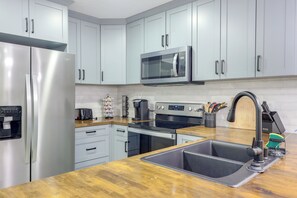 A modern kitchen with stainless steel appliances, a double sink, and light-colored cabinetry. - Walk to Stadiums & Dining: Pet-Friendly Home! (Jacksonville)