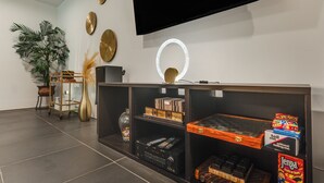 A modern living room with a flat-screen TV, a decorative mirror, and a shelf with board games. - Hike, Boat & Explore! Serene Stafford Apt w/ Patio (Stafford)