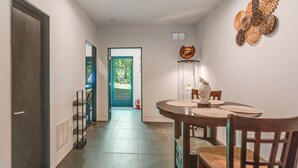 A hallway leading to a dining area with a table and chairs, a staircase, and a door. - Hike, Boat & Explore! Serene Stafford Apt w/ Patio (Stafford)