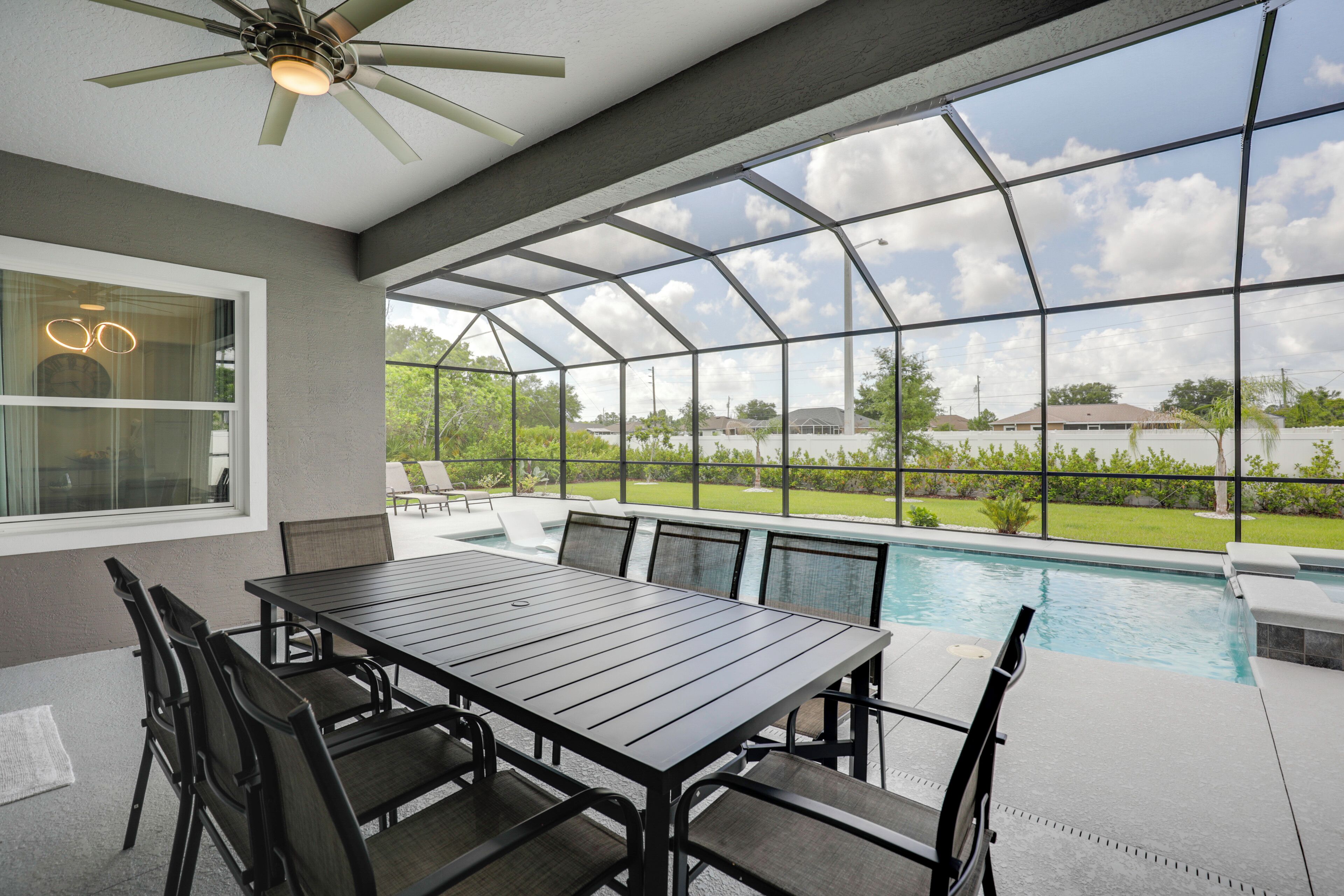 A covered patio with a pool, outdoor seating, and a view of the surrounding landscape.