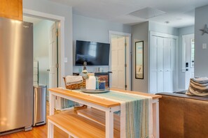 Eine moderne Küche mit einem Edelstahlkühlschrank, einem Einbauofen und einem flachbildfernseher an der Wand.