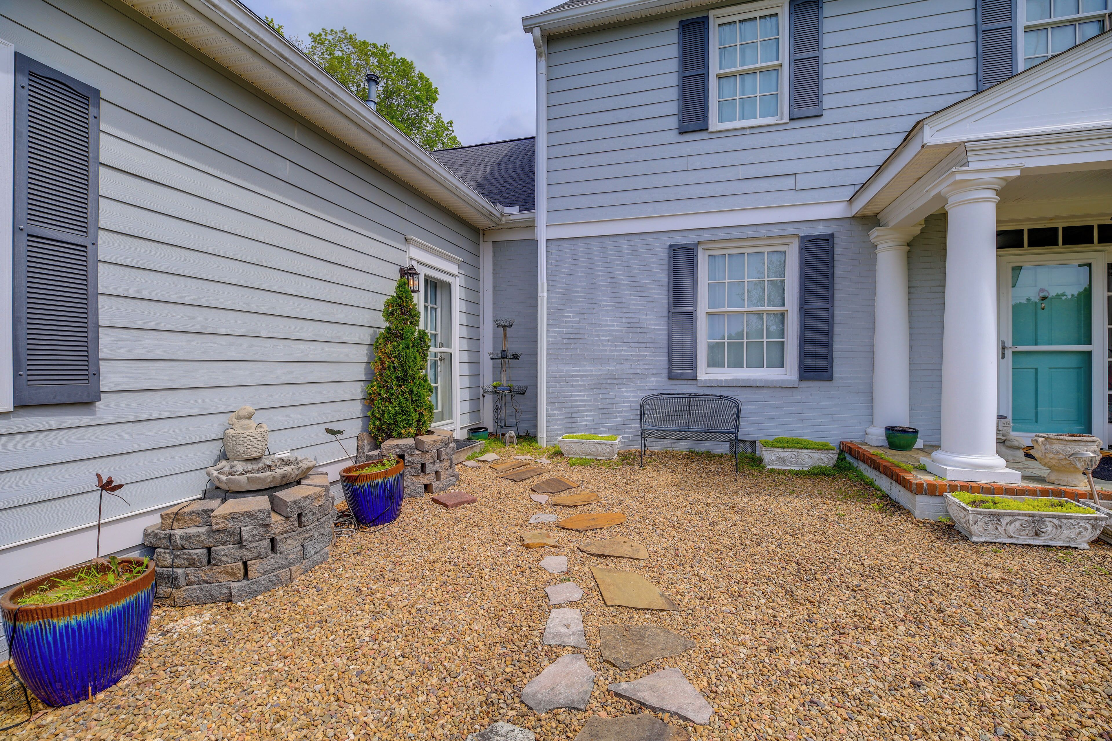 A residential property with a gravel pathway, stone steps, and potted plants.