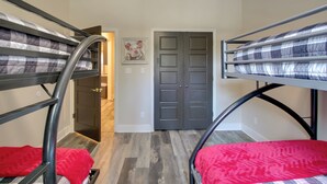 Dormitorio con literas, una puerta, un cuadro y un pasillo.