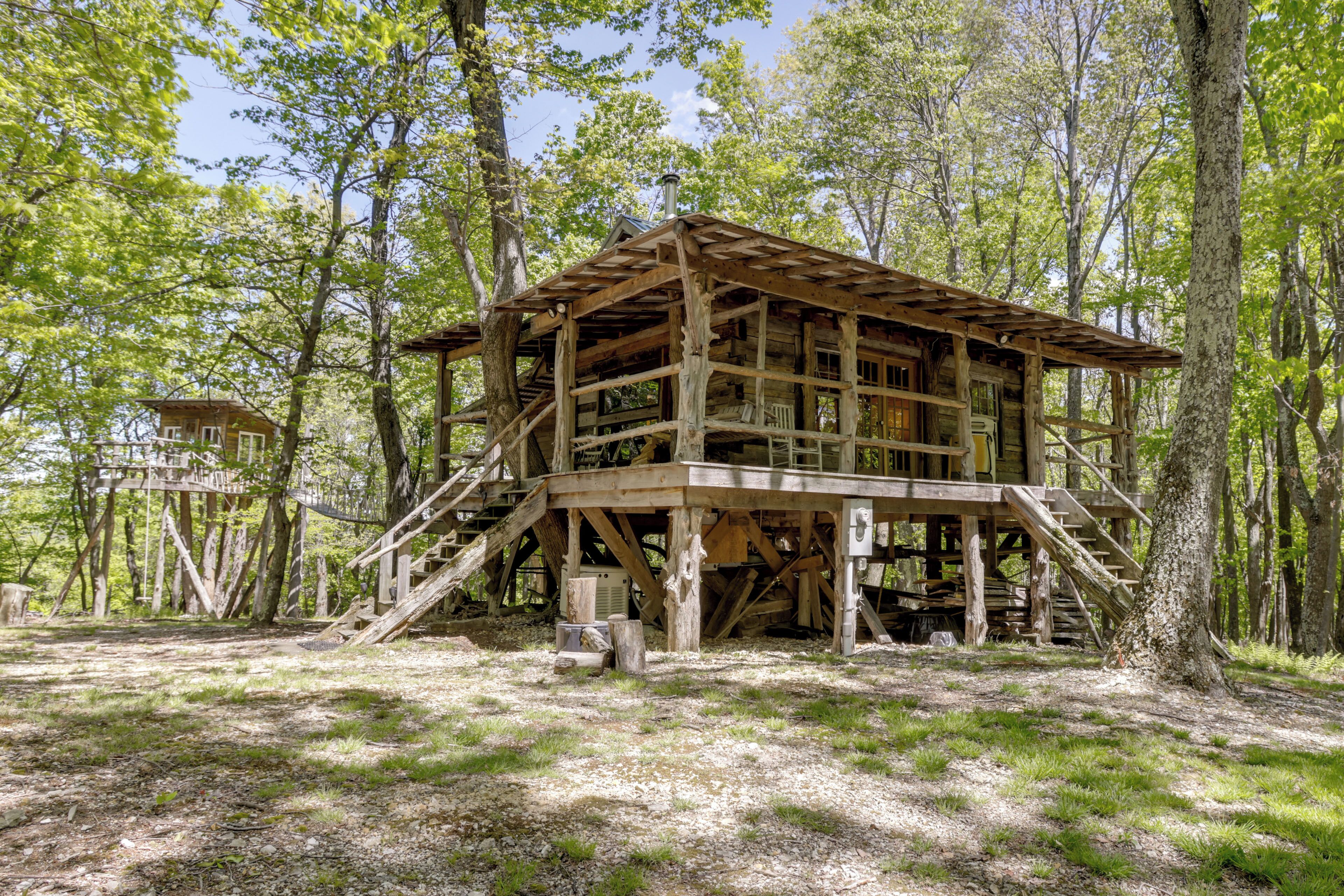 A wooden cabin with a staircase, surrounded by trees.