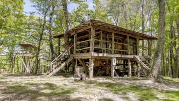 A wooden cabin with a staircase, surrounded by trees.