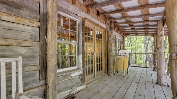 A rustic wooden cabin with a porch, large windows, and a view of the forest. - Mountain Tree House w/ Views in Maysville (Maysville)