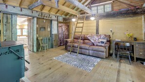 A rustic wooden interior with a lofted ceiling, a leather sofa, a desk, and a ladder. - Mountain Tree House w/ Views in Maysville (Maysville)