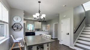 Una cocina moderna con comedor, una escalera y un reloj en la pared.