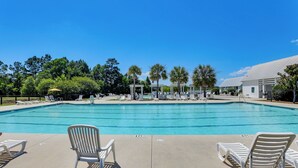 Una piscina con sillas de descanso y palmeras al fondo.