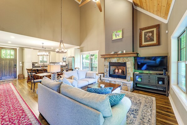 A spacious living room with a fireplace, a television, and a dining area. - Screened Porch! Wooded Getaway in North Cove (Marion)