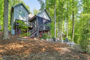 A two-story cabin with a balcony, surrounded by a forested area. - Screened Porch! Wooded Getaway in North Cove (Marion)