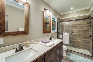 A bathroom with a double sink vanity, a large mirror, a glass shower enclosure, and a toilet. - Screened Porch! Wooded Getaway in North Cove (Marion)