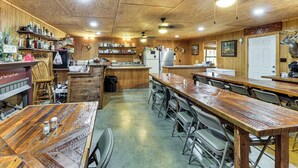 Un intérieur rustique avec des murs en bois, une longue table à manger et un réfrigérateur.