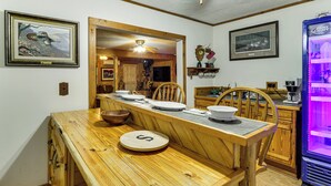 Une table à manger en bois, des chaises, un réfrigérateur et des tableaux encadrés accrochés aux murs.
