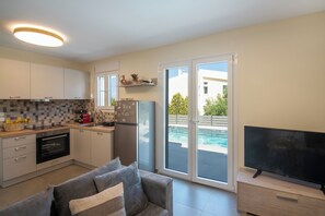 Eine moderne Küche mit Einbauofen, Kühlschrank sowie einem Essbereich mit Tisch und Stühlen.
