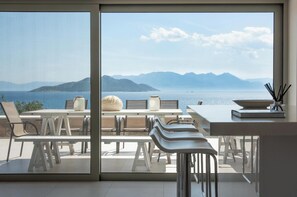 Ein moderner Essbereich mit Blick auf das Meer und die Berge.