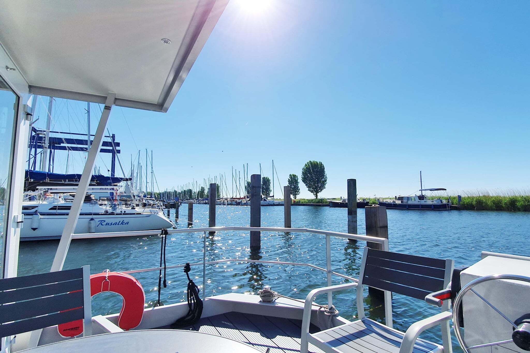 A marina with boats docked, a clear sky, and a calm water body.