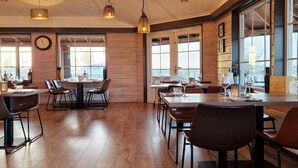 A restaurant with wooden walls, large windows, and hanging pendant lights. - Floating lodge with Terrace in Lelystad (Lelystad)