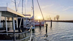 A boat with a dining area, a mast, and a calm water body. - Floating lodge with Terrace in Lelystad (Lelystad)