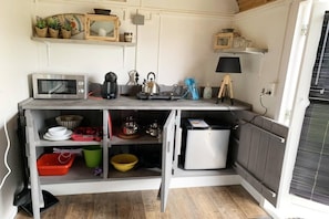 A compact kitchen with a microwave, kettle, and small refrigerator.