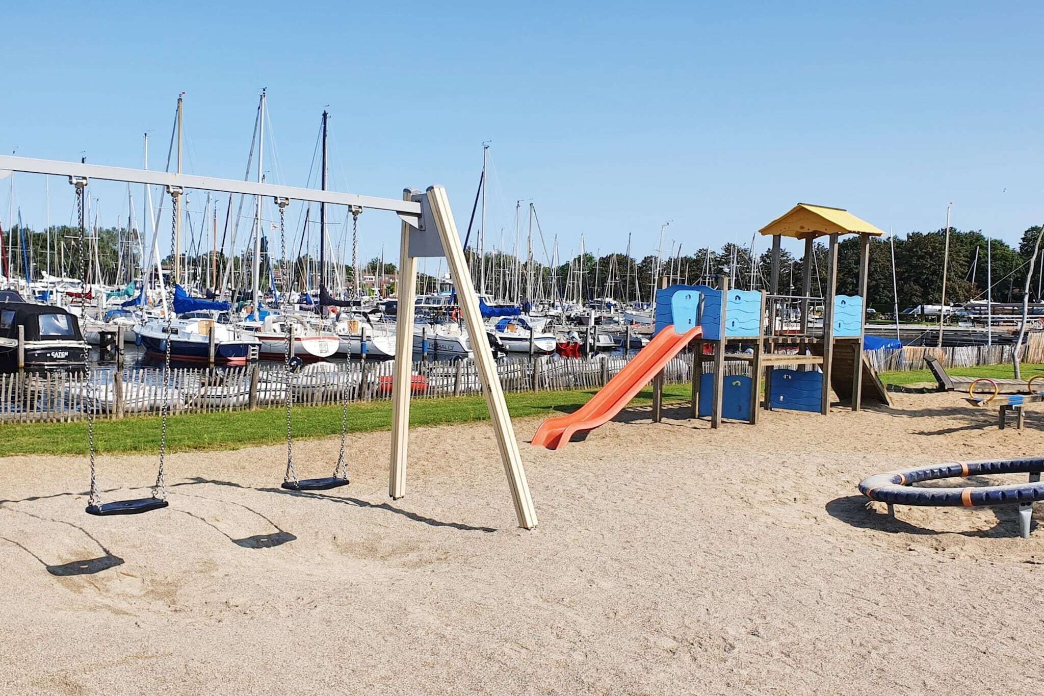 Une aire de jeux avec des balançoires, un toboggan et une structure d’escalade.